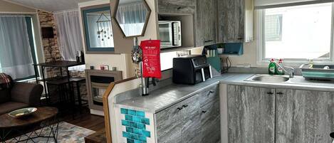 A modern kitchen with a microwave, a fire blanket, and a sink.
