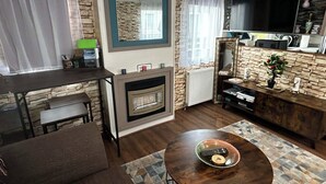 Una sala de estar con chimenea, televisor, comedor y un muro decorativo de piedra.