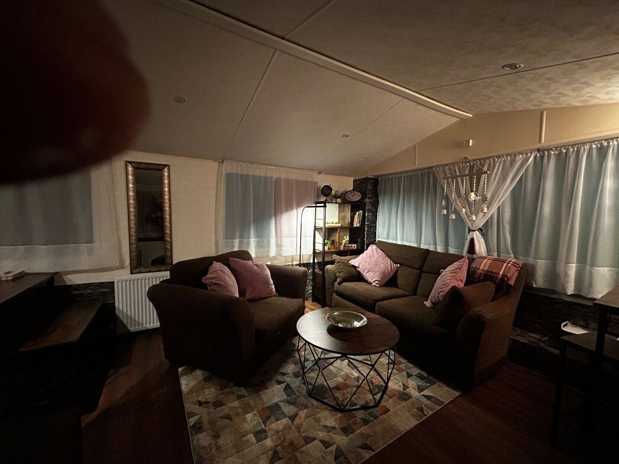 Ein Wohnzimmer mit zwei Sofas, einem Couchtisch, einem Bücherregal und einem Fenster mit Vorhängen.