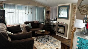 Una sala de estar con sofá, sillón, mesa de centro y chimenea.