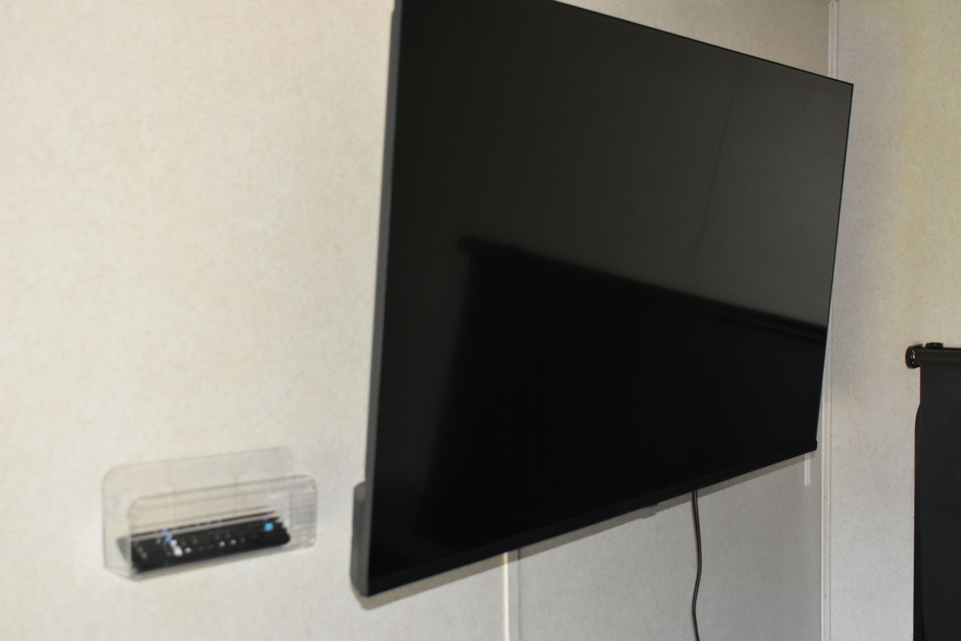 Un téléviseur à écran plat fixé au mur, une prise de courant et une boîte pour organiser les câbles.