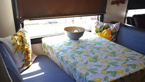 Een kleine, compacte kamer met een enkel bed, een tafel met een kom erop en een raam met uitzicht op buiten.