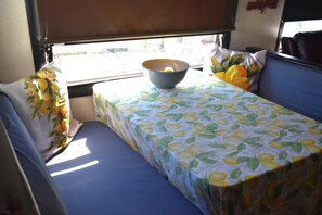 Ein kleines, gemütliches Zimmer mit einem Einzelbett, einem Tisch mit einer Schale darauf und einem Fenster mit Blick nach draußen.