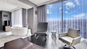 Una camera d'albergo moderna con una grande vasca da bagno, una poltrona comoda e vista sulla città.