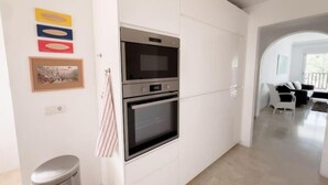 Una cuina moderna amb forns integrats, un cubell de brossa i un quadre a la paret.