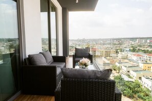 Un balcon agrémenté de meubles en osier et d’un vase de fleurs, d’où l’on peut admirer la vue sur la ville.