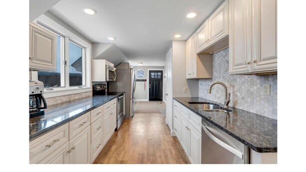A kitchen with white cabinets, a granite countertop, a stainless steel sink, and a microwave. - Sunday River Group Getaway (Bethel)