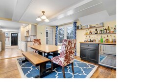 A modern kitchen with a dining area, wooden furniture, and a bar area with liquor bottles. - Sunday River Group Getaway (Bethel)