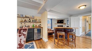A kitchen with a bar area, wooden flooring, and a built-in oven. - Sunday River Group Getaway (Bethel)