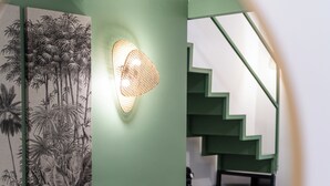 Ein Wohnzimmer mit einer Couch, einer Wandleuchte und einer Treppe.