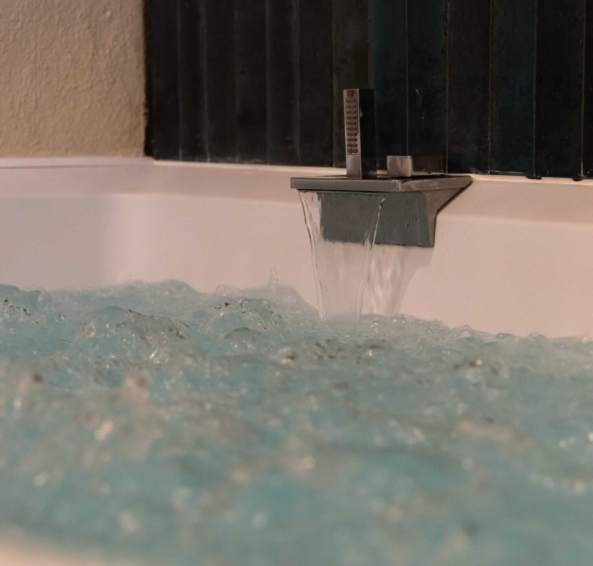 A bathtub with clear water flowing from a faucet.
