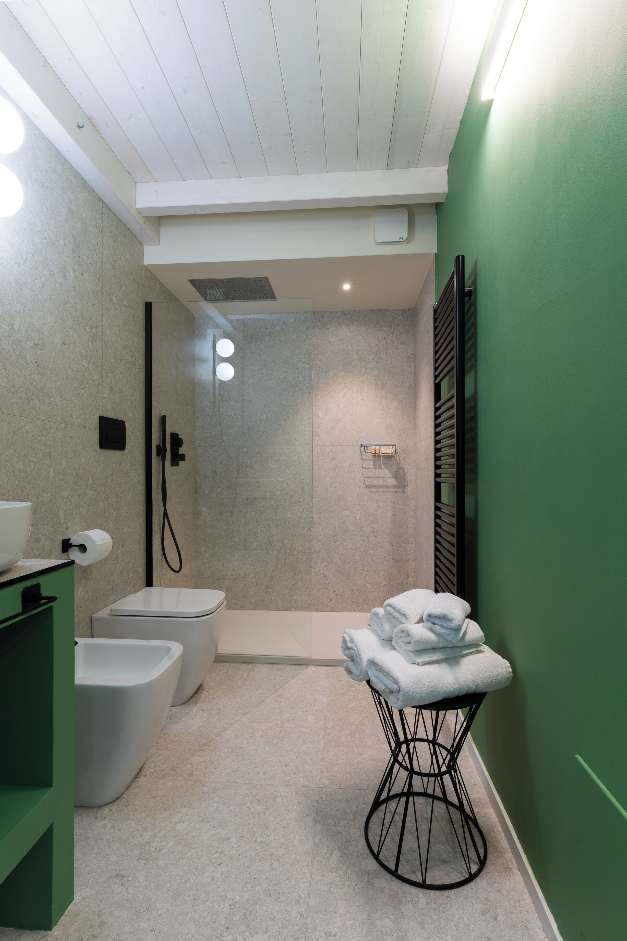 Een moderne badkamer met een douche, bidets, toilet en een handdoekhouder.