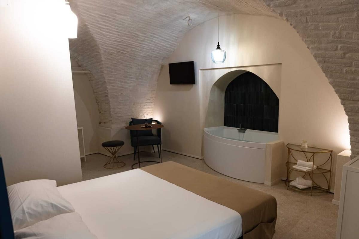 Una camera da letto con un letto, un tavolino, una sedia, una vasca e un televisore.