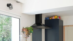 A modern kitchen with dark cabinetry, a stainless steel sink, wooden cutting boards, and a window with a view of greenery. - Group holiday in the garrigue - 12 people - total peace and quiet (Saint-Martin-de-Londres)