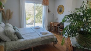 A bedroom with a bed, a dining table, chairs, a hanging light fixture, a potted plant, and a window with curtains. - Group holiday in the garrigue - 12 people - total peace and quiet (Saint-Martin-de-Londres)