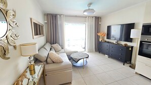 Uma sala de estar moderna com sofá, televisão e área de jantar.