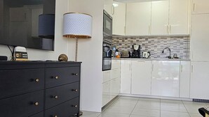 Cozinha moderna com armários brancos, bancada preta e piso ladrilhado.
