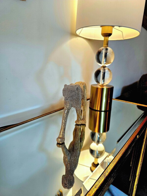 Eine Lampe mit reflektierendem Sockel und einer verzierten Metallfigur.