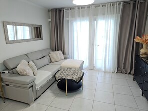 A modern living room with a grey sofa, a round coffee table, and a black side table with a vase. - Amarilla Golf Tenerife apartment with sea views, swimming pool and terrace (Amarilla Golf)