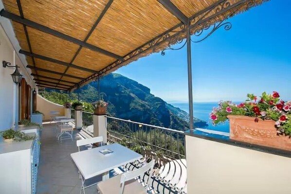 A terrace with a view of the sea, outdoor seating, and potted plants. - De Vivo Realty - Villa Savina Positano (Positano)