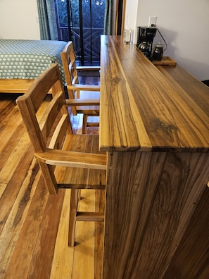 Una mesa de madera para comer con sillas, una cafetera y vistas a un balcón.