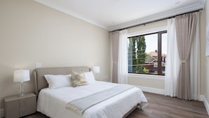 Quarto com uma cama grande, abajures, mesa de cabeceira e janela com cortinas.