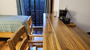 Ein Holztisch mit Stühlen, einer Kaffeemaschine und Blick auf einen Balkon.