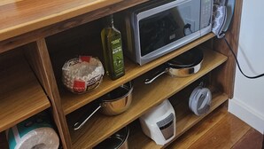 Eine Küche mit einer Holzausziehtafel, einer Mikrowelle, einer Kaffeemaschine und verschiedenen Küchenutensilien.