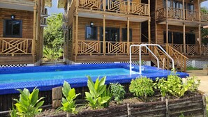 Ein holzhäuschen-ähnliches Hotel mit Schwimmbad, Balkonen und einem Garten.