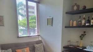 A living room with a sofa, a dining table, and a window with blinds. - Family-friendly Condo With Pool View, Walk to Jaco Beach (Jacó)