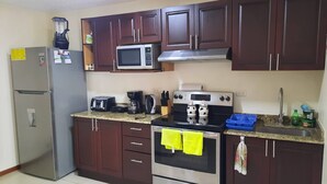 A kitchen with a refrigerator, microwave, toaster, coffee maker, stove, and cabinets. - Family-friendly Condo With Pool View, Walk to Jaco Beach (Jacó)