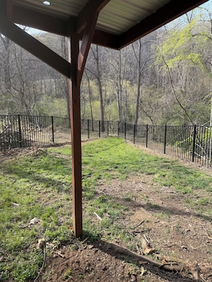 A covered outdoor area with a wooden structure, a fenced yard, and a forested background. - Delightful 3-bedroom home with a fenced in yard in Leicester (Leicester)