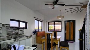 Eine moderne Küche mit Marmorarbeitsplatte, ein Essbereich mit Holzmöbeln und einem Deckenventilator.