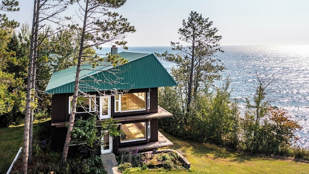 A two-story house with a green roof, large windows, and a view of the ocean. - Stunning Lakehouse in Castle Danger (Two Harbors)
