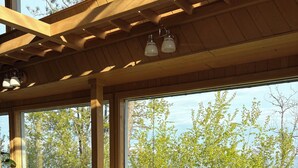 A modern interior with large windows, a wooden ceiling, a blue armchair, a wooden coffee table, and a small table with a lamp. - Stunning Lakehouse in Castle Danger (Two Harbors)