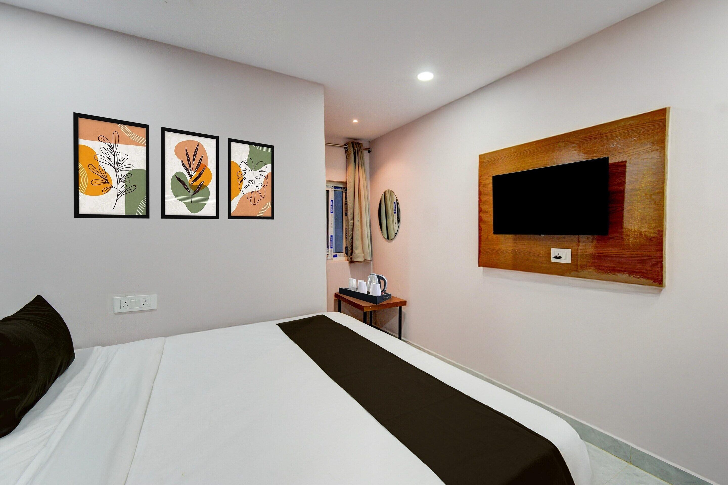 Une chambre d’hôtel comprenant un lit, un téléviseur à écran plat fixé au mur et trois œuvres d’art encadrées accrochées au mur.