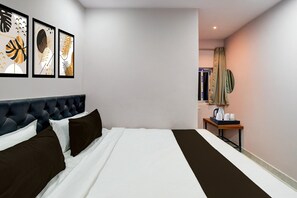 A hotel room with a bed, a bedside table with a kettle, and framed artwork on the wall. - Hotel O Injapur Lake (Hyderabad)
