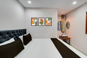 A hotel room with a large bed, a small table with a kettle, and three framed artworks on the wall. - Hotel O Injapur Lake (Hyderabad)