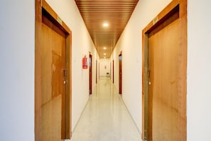 A hallway with wooden doors, a fire extinguisher, and a ceiling with recessed lighting. - Hotel O Injapur Lake (Hyderabad)