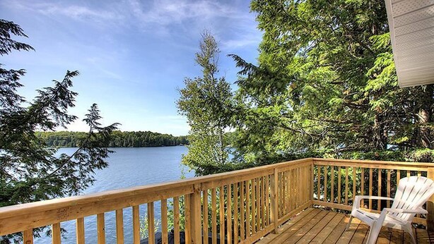 Une terrasse en bois offrant une vue sur un lac, entourée d’arbres.