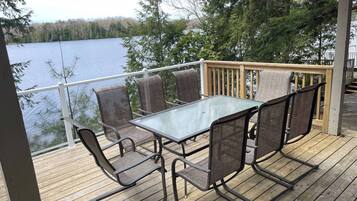 Une terrasse avec une table et des chaises en verre, donnant sur un lac.