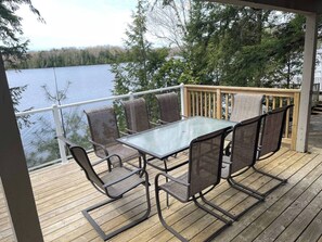 A deck with a glass table and chairs, overlooking a lake. - Luxury Waterfront Retreat in Highlands East - Ridgestone Cottage (Highlands East)