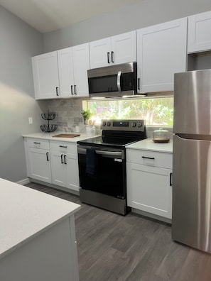 A modern kitchen with white cabinets, stainless steel appliances, and a wooden countertop.