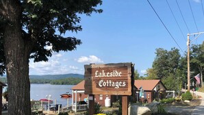 Une enseigne en bois indiquant « Lakeside Cottages » et offrant une vue sur un lac et des chalets.