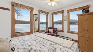Une chambre dotée d’un grand lit, d’un ventilateur de plafond et offrant une vue sur un paysage enneigé grâce à de nombreuses fenêtres.