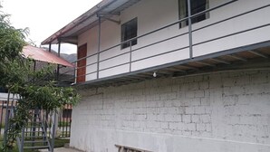 A two-story building with a balcony, a staircase, and a brick wall. - Tampu Wasi Luci (Distrito de Coya)