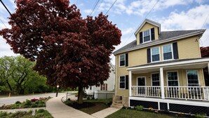 A two-story house with a front porch, a driveway, and a tree with red leaves. - Riverfront Escape Near Boston & Transit w/ Parking (Medford)