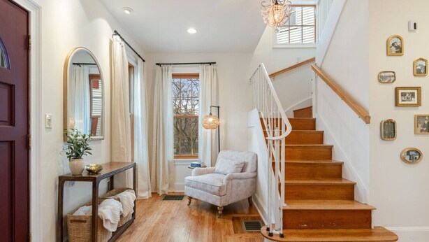 A wooden staircase with a white railing, a gray armchair, and a mirror on the left wall. - Riverfront Escape Near Boston & Transit w/ Parking (Medford)