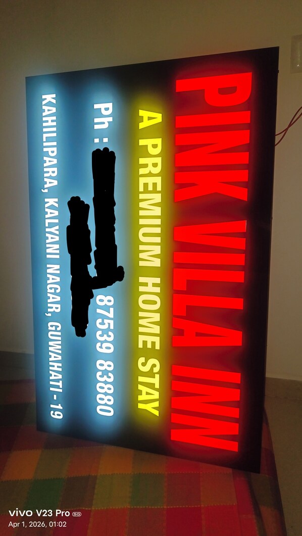 A sign for Pink Villa Inn with a contact number and a premium home stay option. - Fabulous 4-bedroom studio with AC in vibrant Guwahati (Guwahati)