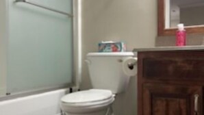 Une salle de bain avec des toilettes, une douche et un meuble en bois.